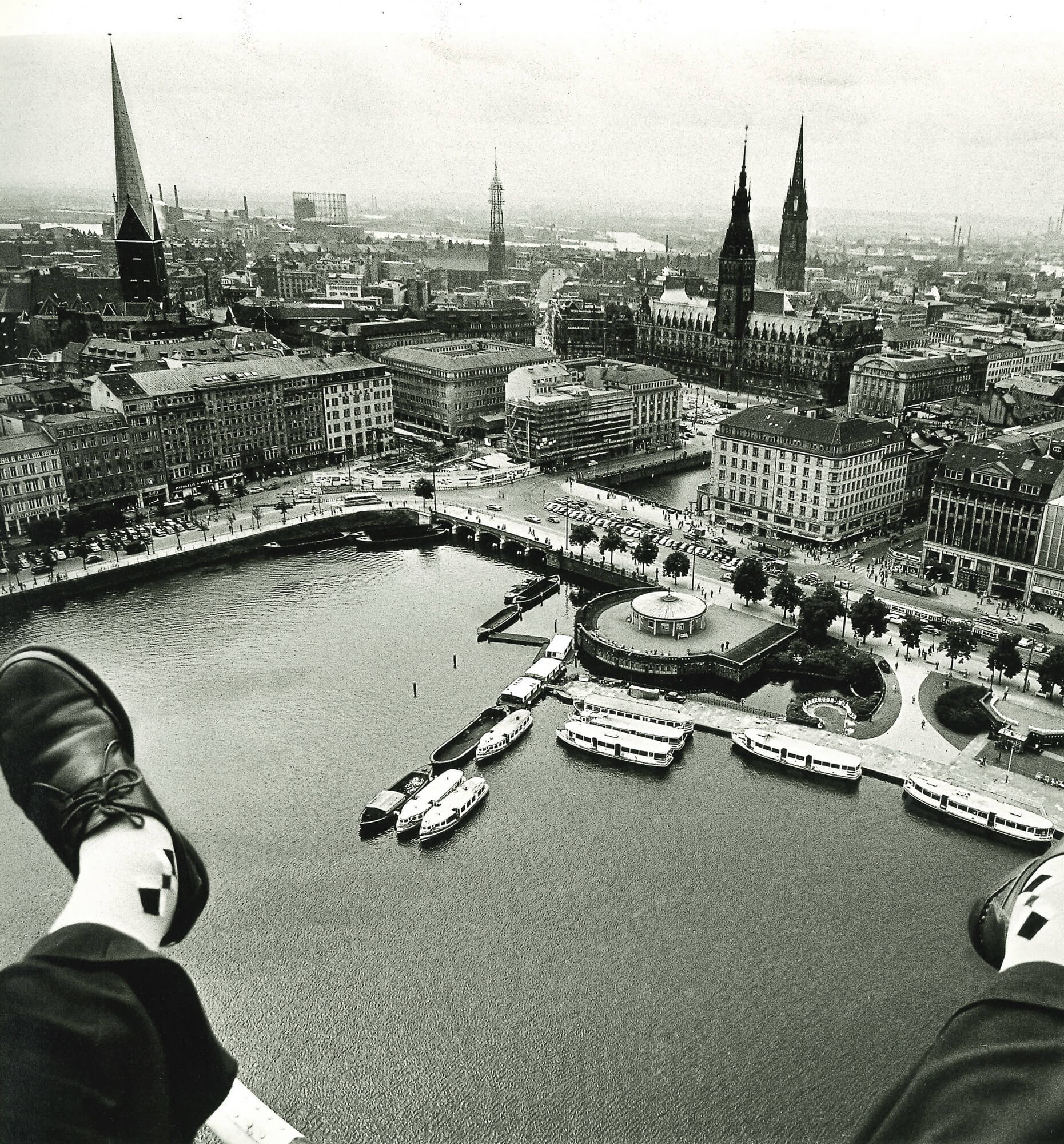 Zwischen den noch sichtbaren Füßen des Fotografen hindurch aus der Luft fotografiert: Innenalster, Jungfernstieg und das Hamburger Rathaus