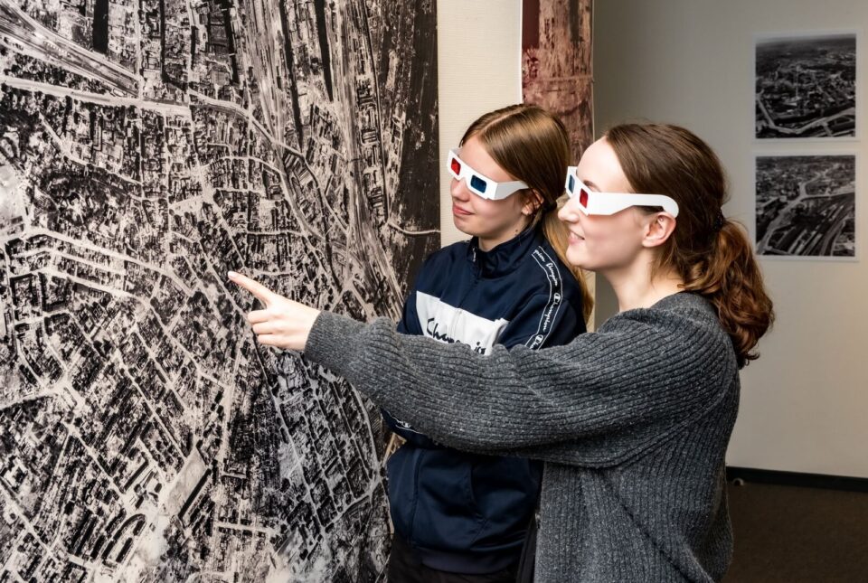 Zwei Besucherinnen betrachten eine Luftaufnahme mit 3D-Brillen