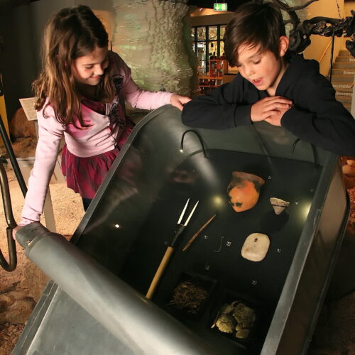 Zwei Kinder entdecken in der Ausstellung archäologische Funde.