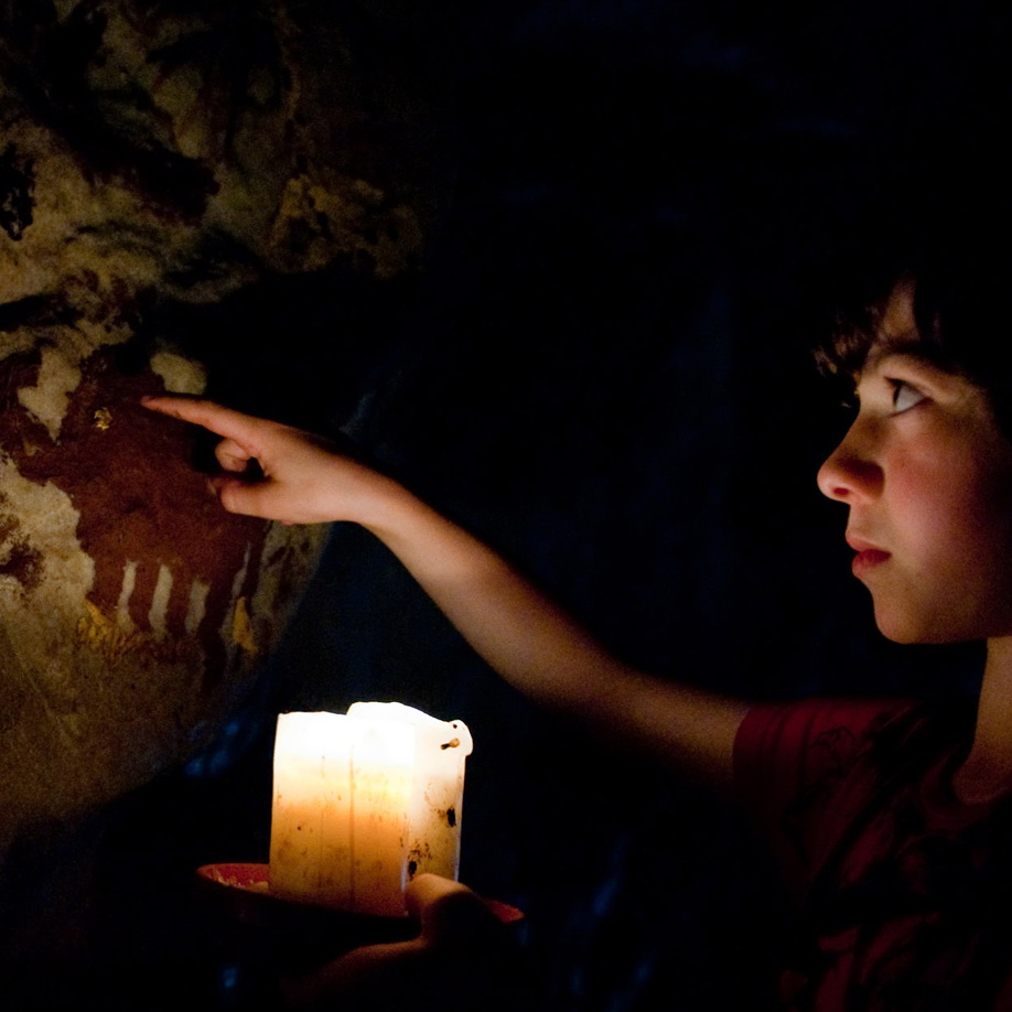 In der Eiszeithöhle des Museum. Ein Kind zeigt auf eine Zeichnung an der Höhlenwand.