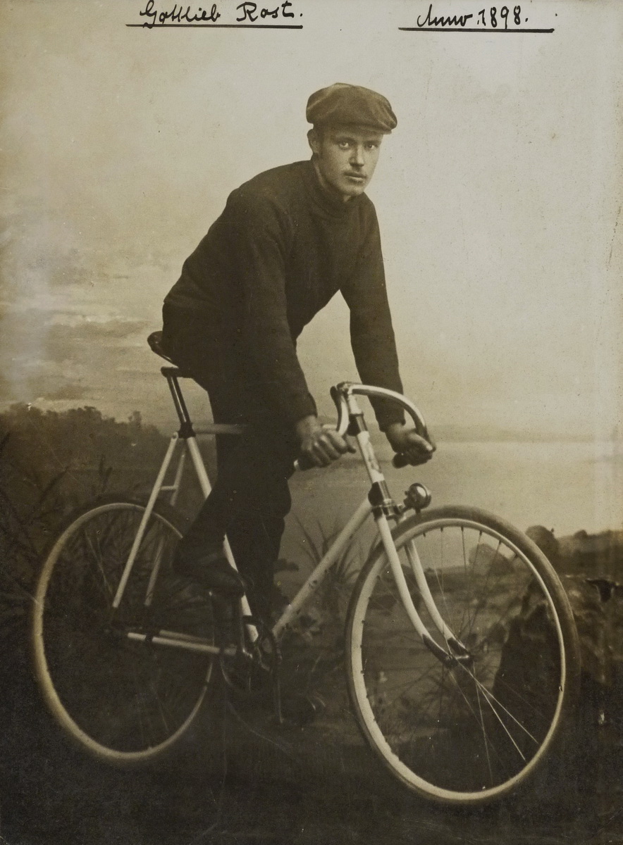 Ein Radfahrer posiert auf seinem Rennrad vor einer Fotoleinwand mit Landschaftsbild